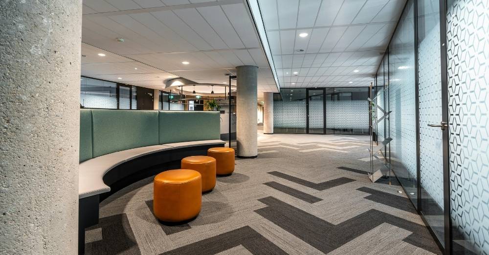 A modern office waiting area with a large, curved gray and mint green bench.