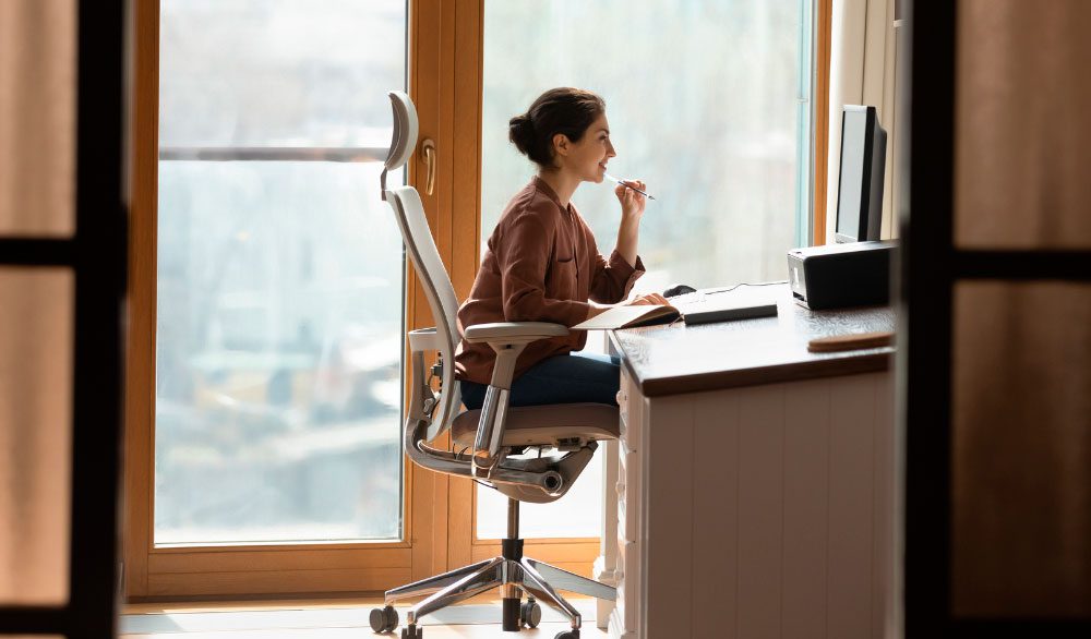 A woman works at a desk, looking at a computer.