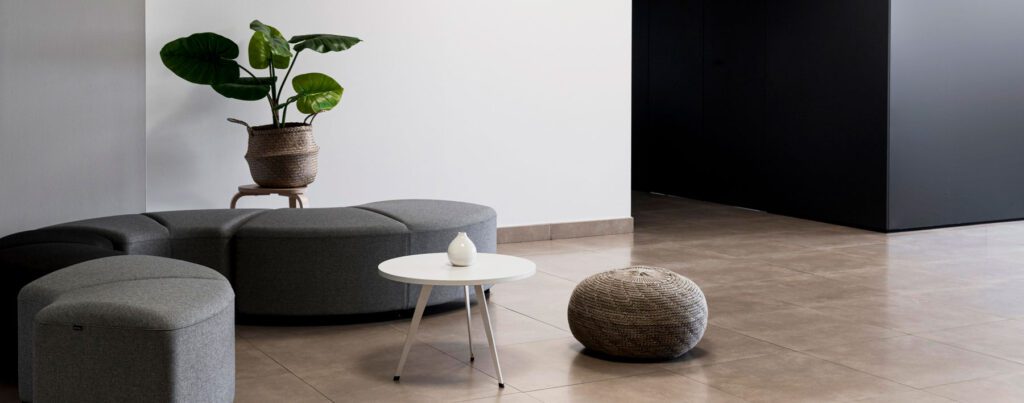 A lounge with a gray sofa, a small table, and plants.