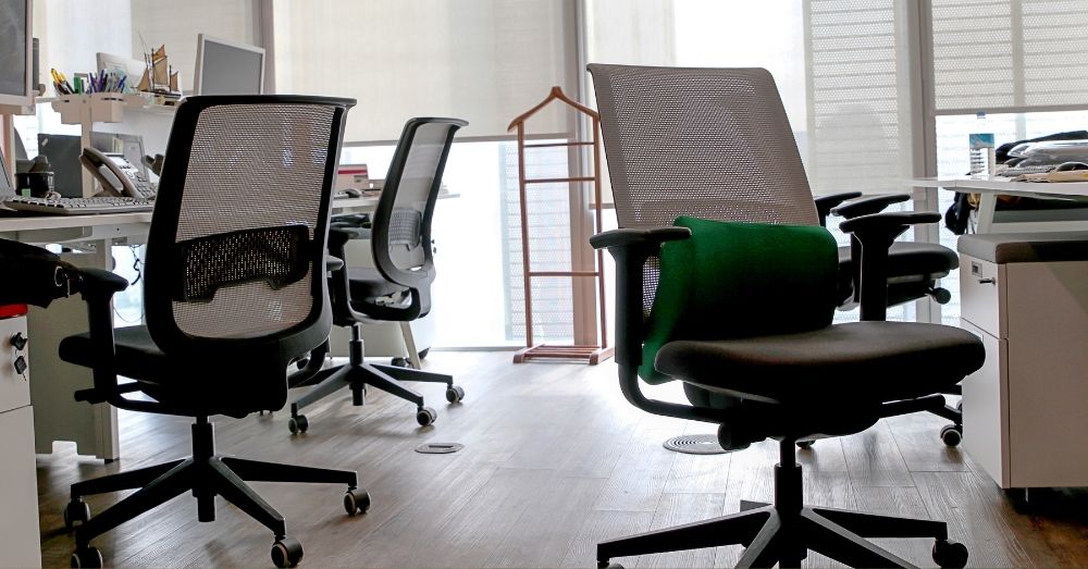 Empty Herman Miller style mesh office chairs in a bright office.