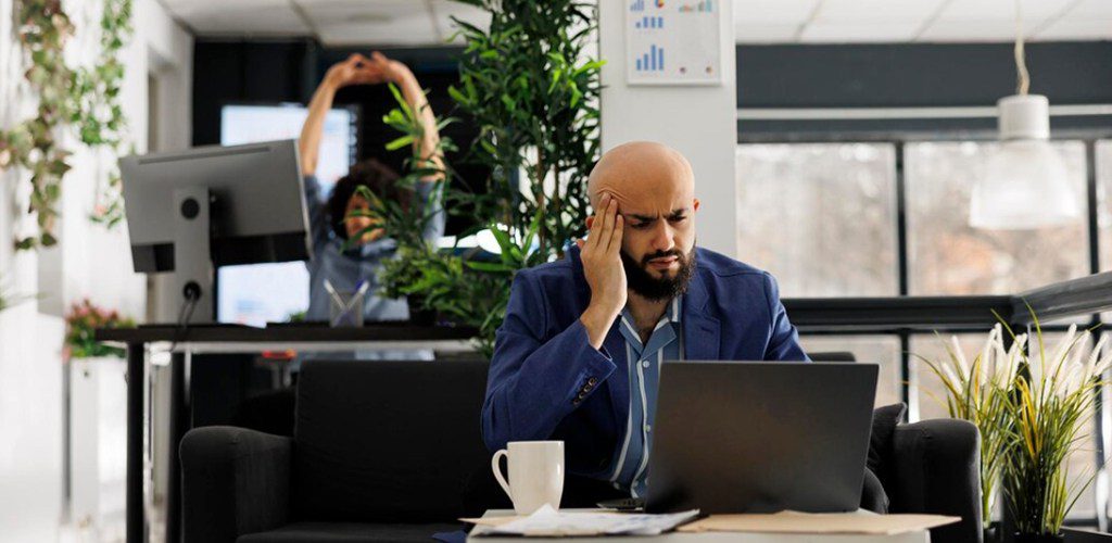 Worker massaging his head while working
