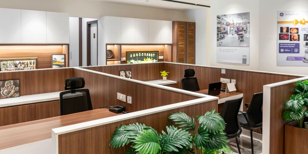 A modern office interior featuring warm wood-paneled cubicles with white countertops
