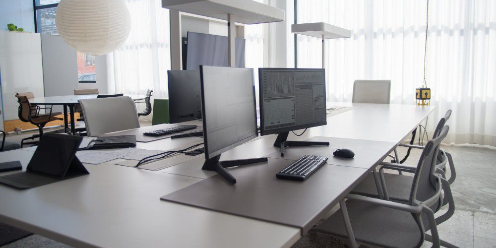 open-concept office space featuring long white shared desks
