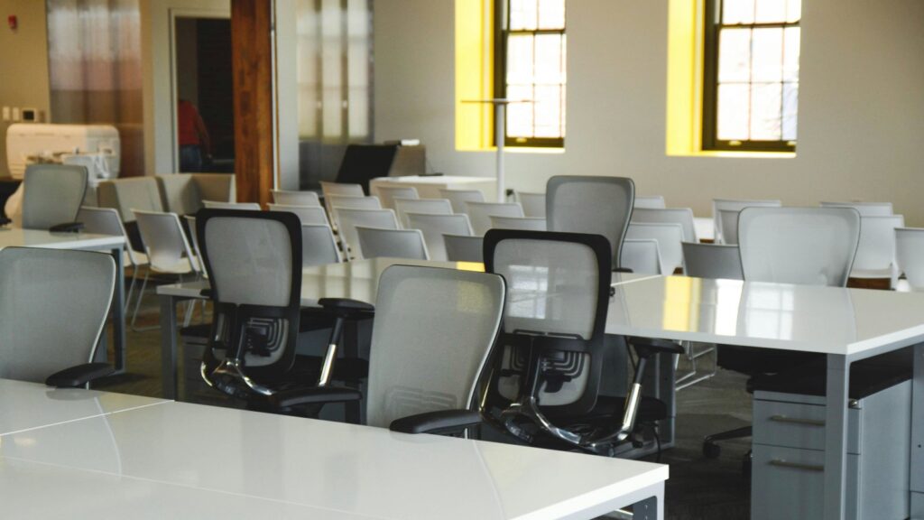 Spacious open office workspace with desks, chairs, and natural lighting