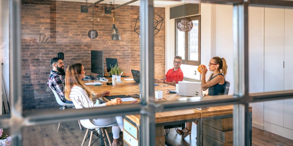 group of coworkers collaborating around a large wooden desk